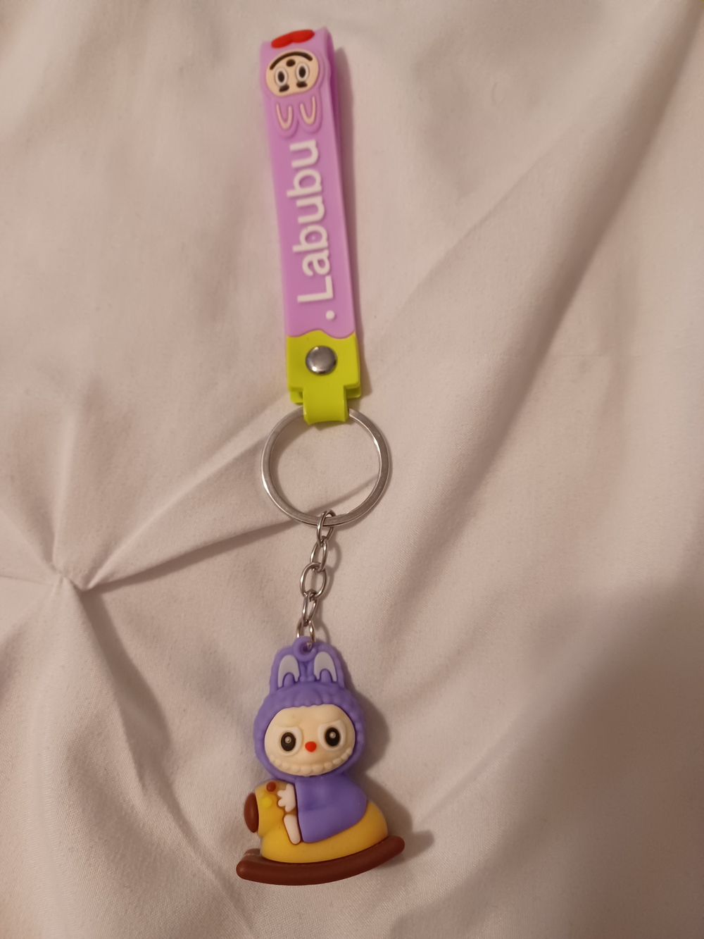 Labubu keychain featuring a purple hooded character charm and a matching wrist